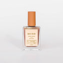 A bottle of BKIND Vegan & 21-free Nail Polish in color pearly rose gold, with a capacity of 15 ml.