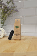A spool of dental floss placed in front of a cardboard packaging labeled 'Me Mother Earth - Eco Floss- Refill ONLY - One Refill' on a wooden surface with a brick wall in the background.
