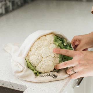 Cauliflower wrapped in a reusable produce bag on a kitchen counter